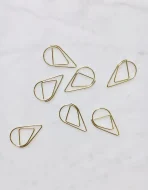 Gold teardrop paperclips arranged on luxury wedding invitation suite