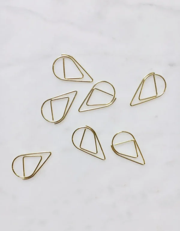 Gold teardrop paperclips arranged on luxury wedding invitation suite